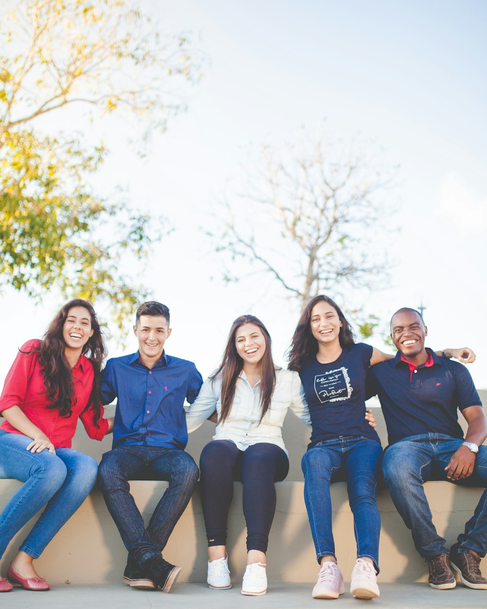 Five smiling high school students sitting together outdoors
