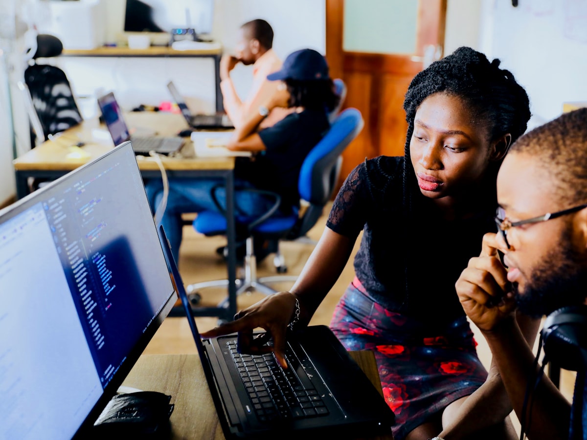 A mentor guiding a student through work on a laptop